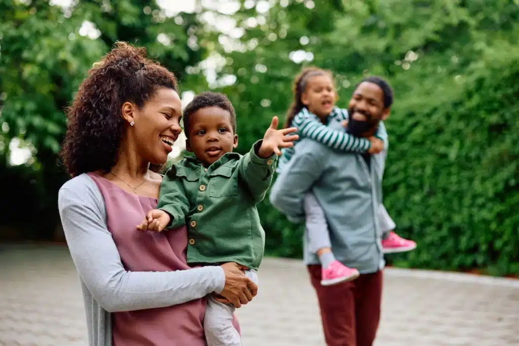 mother and father walk outdoors holding their son and daughter in their arms